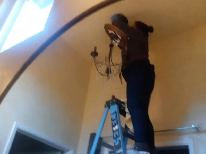 Electrician installing a chandelier in a Fort Lewis residence